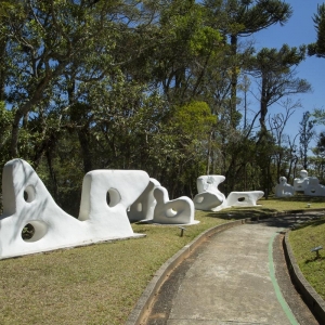 Esculturas da fase "Bichos" de Felícia Leirner espalhadas pelo gramado em meio a vegetação nantiva.