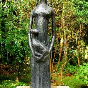 Escultura "Moça com animal" de Felícia Leirner. Feita em bronze, a escultura se assemelha a uma menina que segura em seus braços um animal.