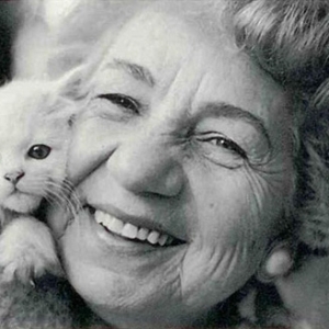 A imagem está preto e branco, na qual há Felícia Leirner, uma mulher já idosa de cabelos curto e cacheados. Ela segura próximo ao seu rosto um filhote de gato.