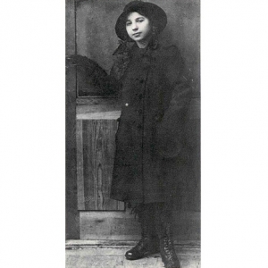 A imagem está em preto e branco e mostra Felícia Leirner quando criança. Uma menina vestida com um sobretudo e botas. Ela usa um chapéu.