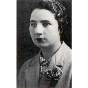 A imagem está em preto e branco e mostra Felícia Leirner jovem. Ela é uma mulher de cabelos cacheados e aparentemente curtos; olhos claros; usa um blazer com uma flor presa sobre ele.