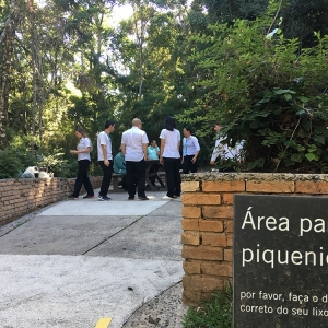 piquenique-Imagem da placa de área para piquenique. Ao fundo pessoas estão ao redor de uma mesa.