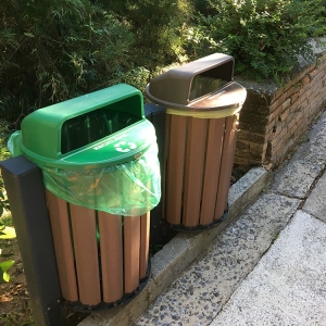 Lata de lixo verde com adesivo escrito "orgânica" e uma lata de lixo na cor marrom escrito "reciclável".