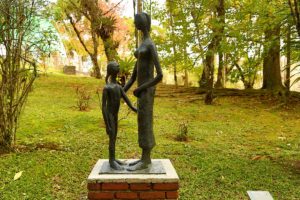Escultura "Mãe e Filha" de Felícia Leirner. A escultura é feita em bronze e aparentemente representa uma filha pequena de frente para sua mãe, alta.