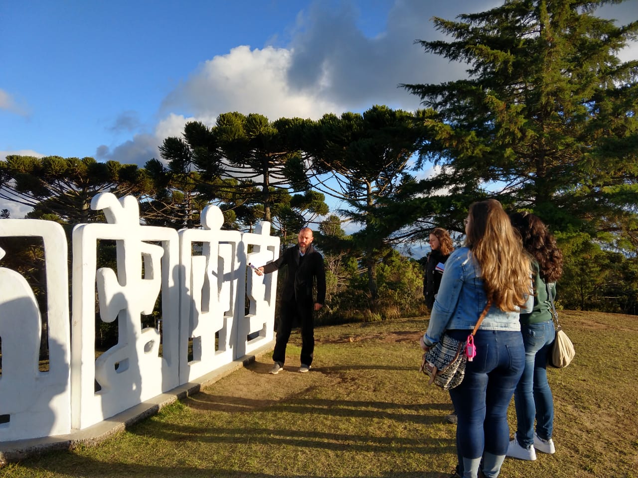 Um educador explica as características da escultura Horizonte a um grupo pequeno de pessoas.