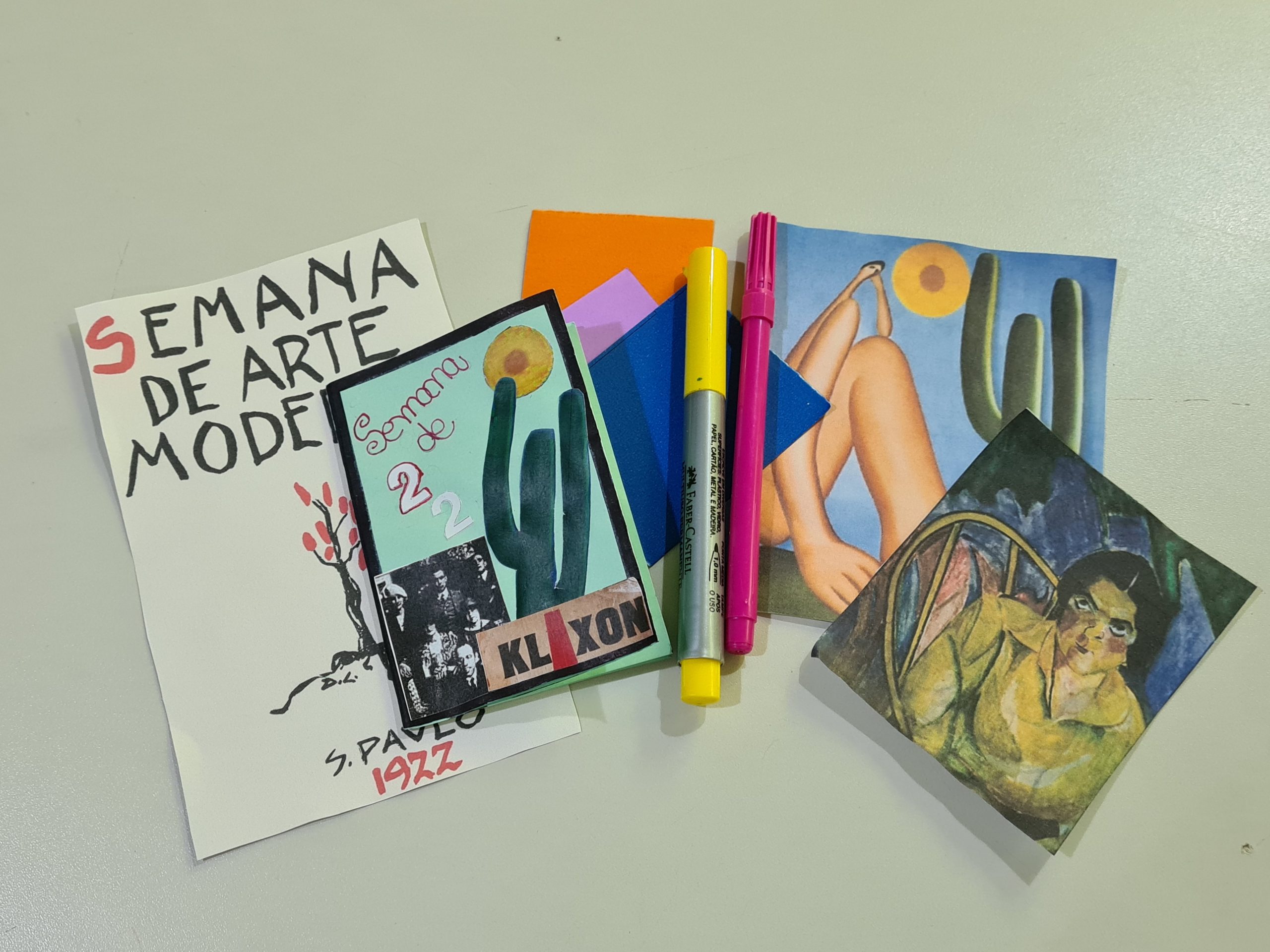 Foto com imagens e recortes referentes a semana de arte moderna. Nela há um cartaz pequeno da semana se arte moderna, uma fanzine, recorte da obra "Abaporu" de Tarsila do Amaral e de "A Boba" de Anita Malfatti.