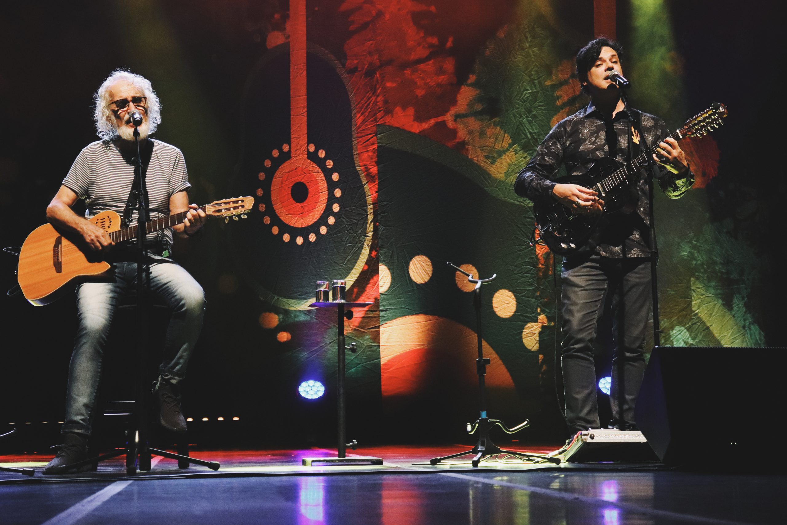 Na imagem, Renato Teixeira e Yassir Chediak estão se apresentando em um palco