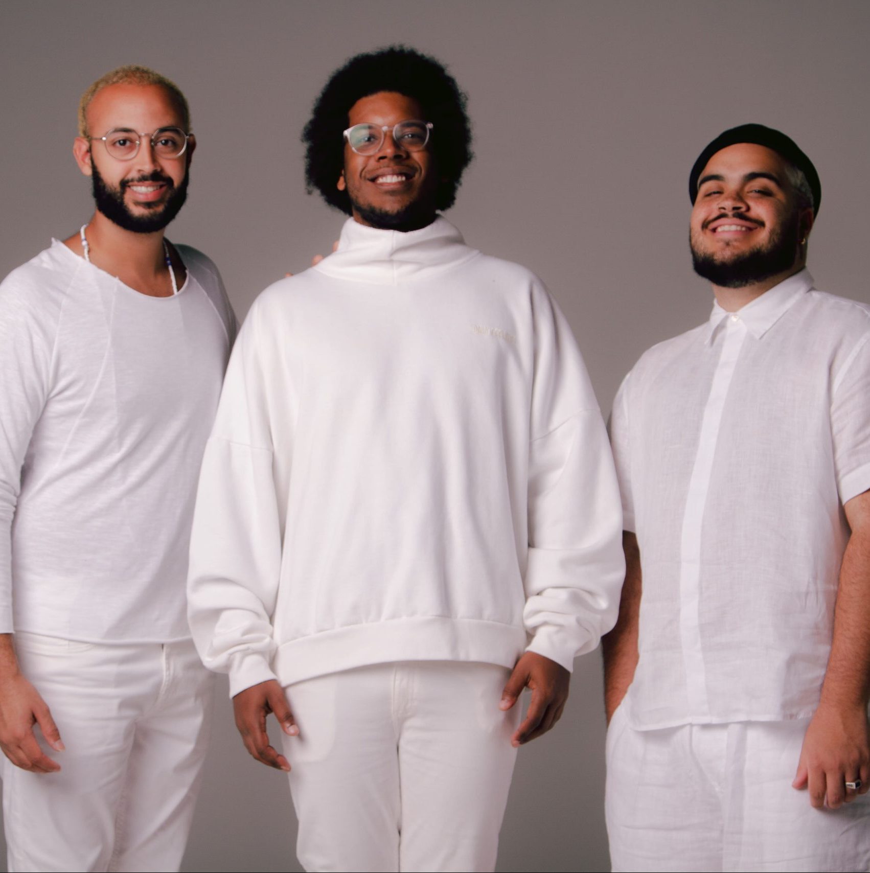 Na imagem estão os Gilsons, três homens negros que vestem roupas brancas.