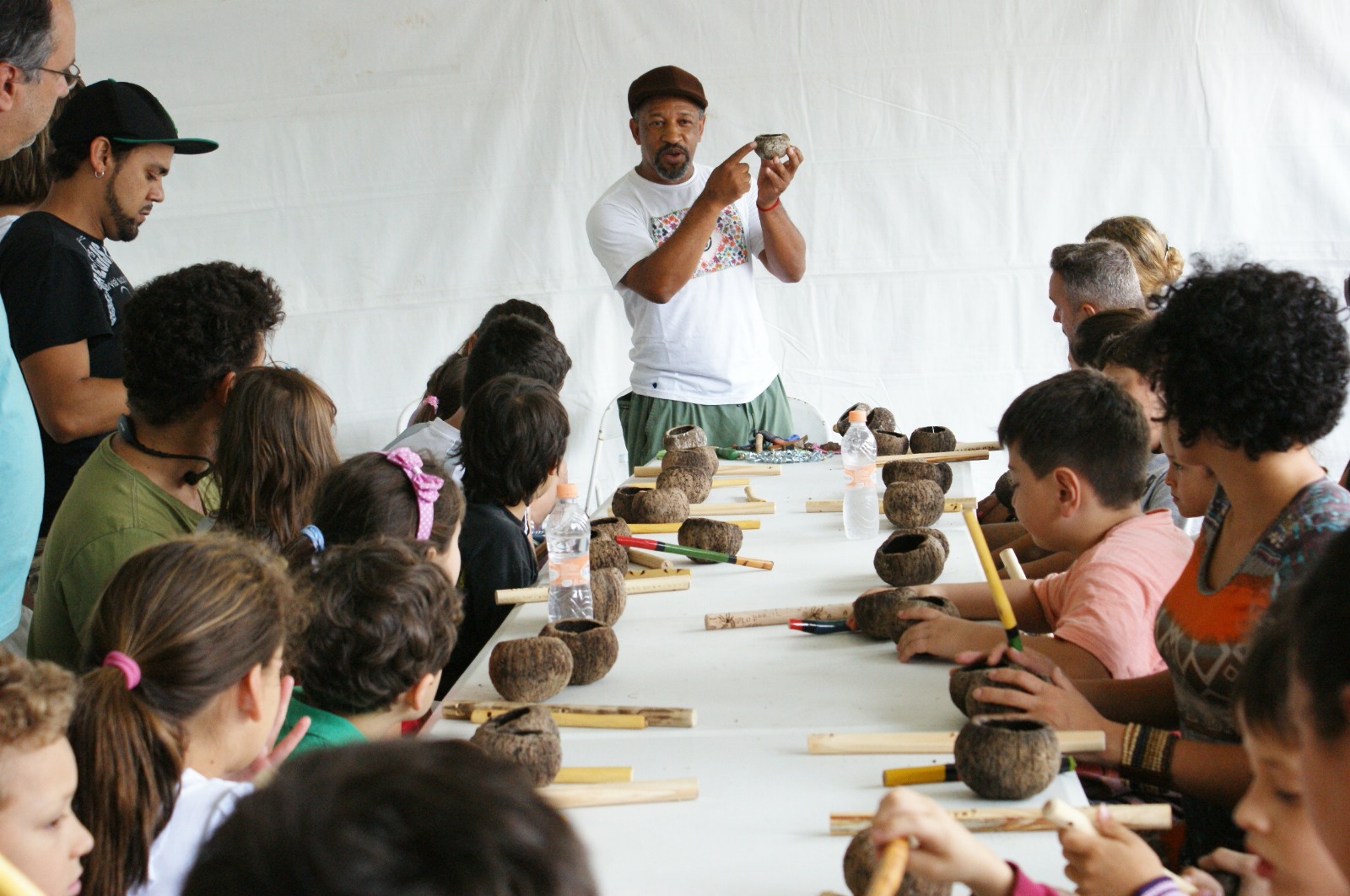 Na imagem Afonsinho Menino ensina um grupo de pessoas a confeccionar um agogô.