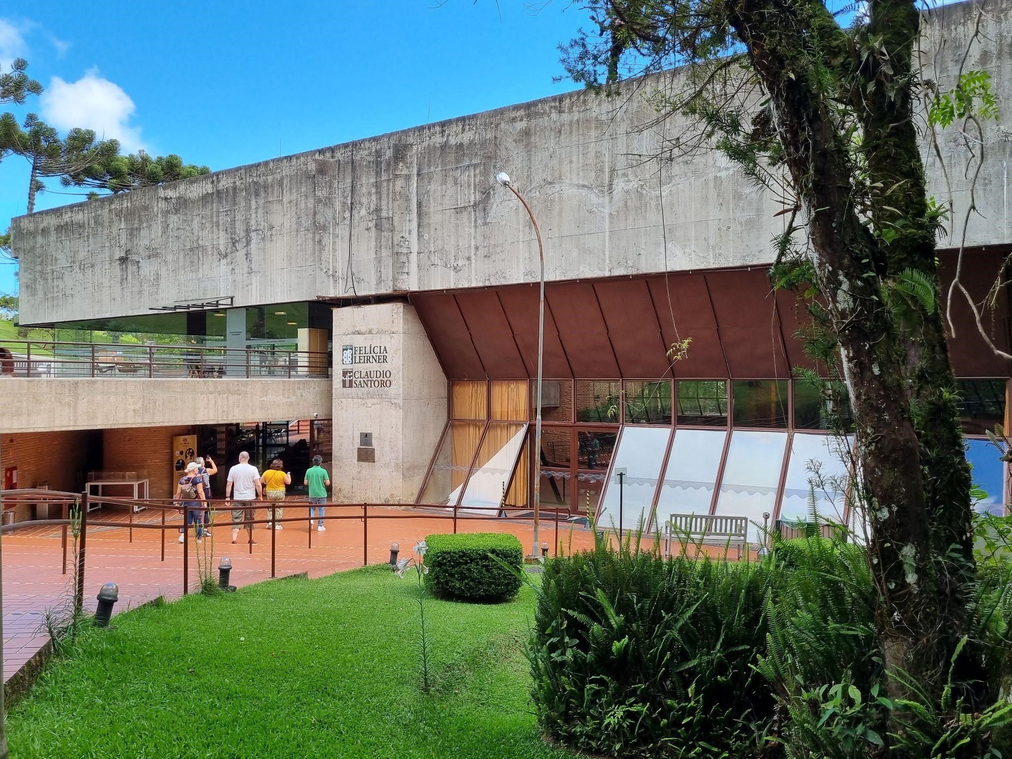 Imagem da fachada do museu e auditório, com visitantes entrando no local