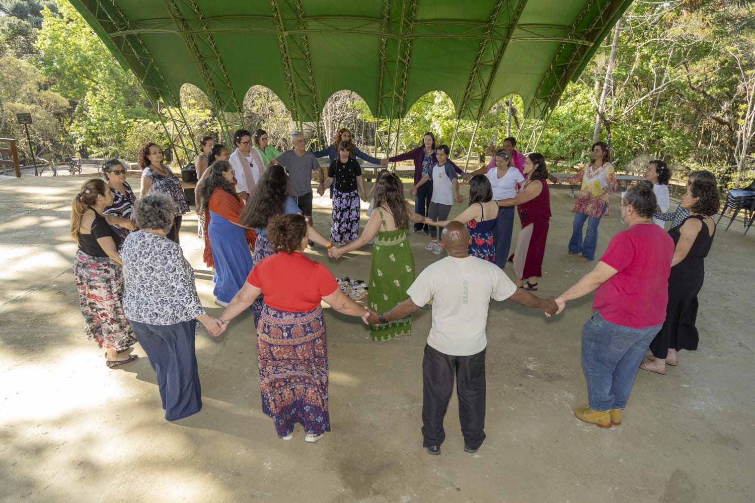 Grupo de pessoas participam de dança circular no espaço de apresentações ao ar livre do museu.