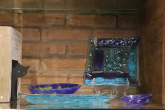 Imagem de  um objeto de decoração, no formato de um pequeno prato, feito em vidro na cor azul.